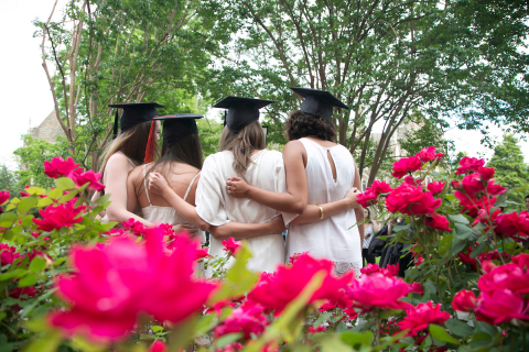 4 female graduates posing for a picture among azaleas